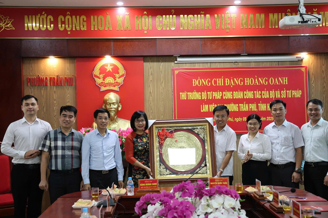 Thứ trưởng Bộ Tư pháp và đoàn làm việc tặng quà lưu niệm cho phường Trần Phú, tỉnh Hà Tĩnh. Ảnh: Hữu Anh