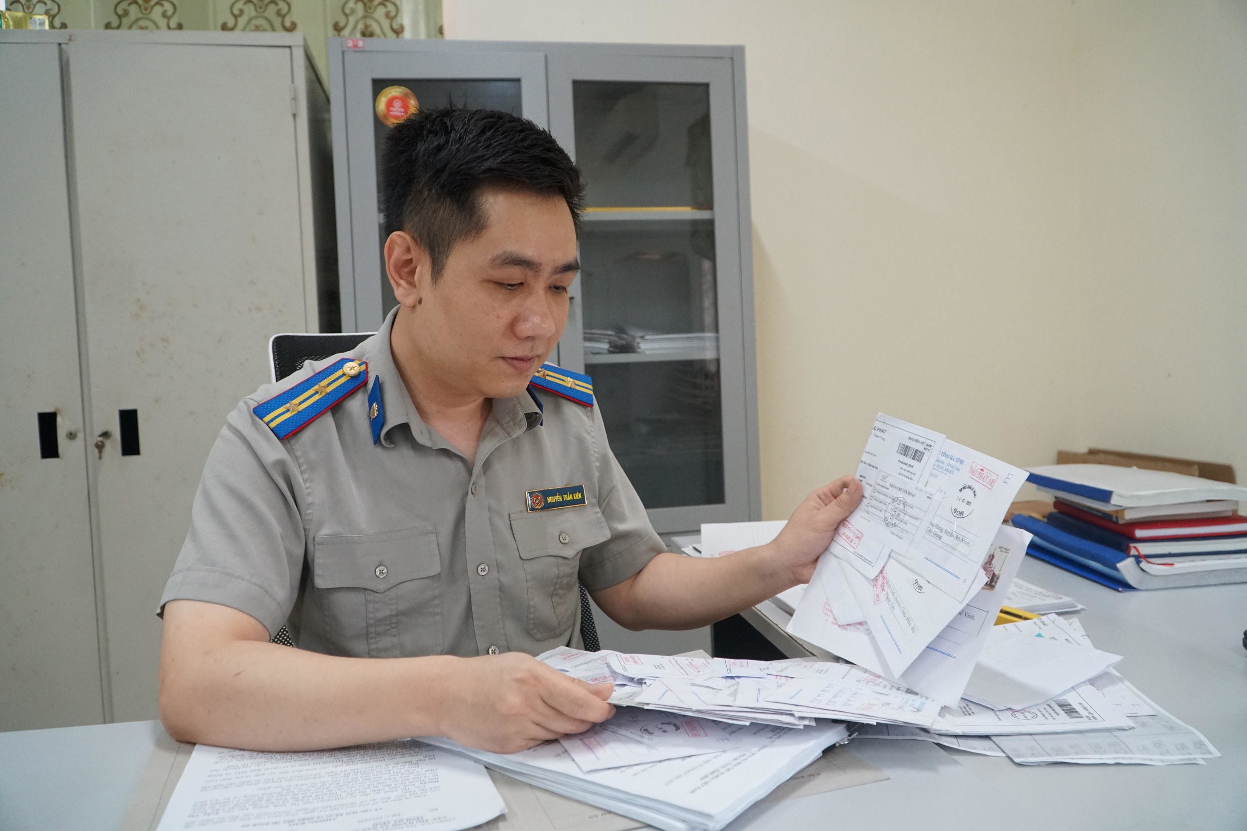 Chấp h&agrave;nh vi&ecirc;n Nguyễn Trần Ki&ecirc;n xem lại những th&ocirc;ng b&aacute;o bị trả về. Ảnh: Tuyết Lan